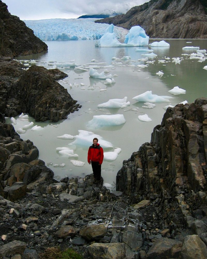 Jared in a red jacket at Grey Glacier, Patagonia, 2003, icebergs behind him.